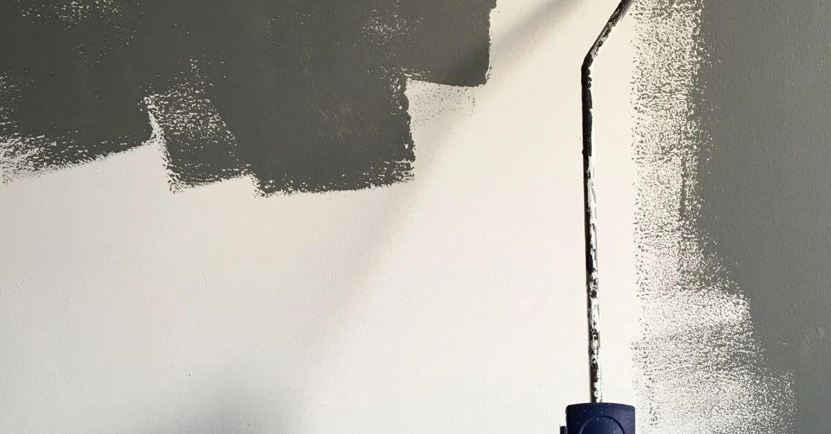 A hand applying paint with a roller, illustrative photography